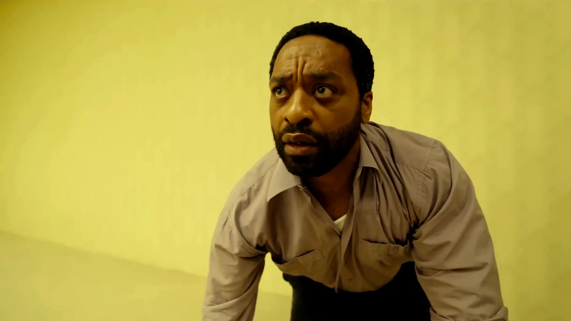 Clark (Chiwetel Ejiofor) leans forward with a wide, frightened stare under yellow light