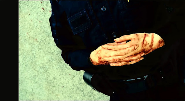 A uniformed police officer with blood on his hands at a crime scene in Blood Sacrifice