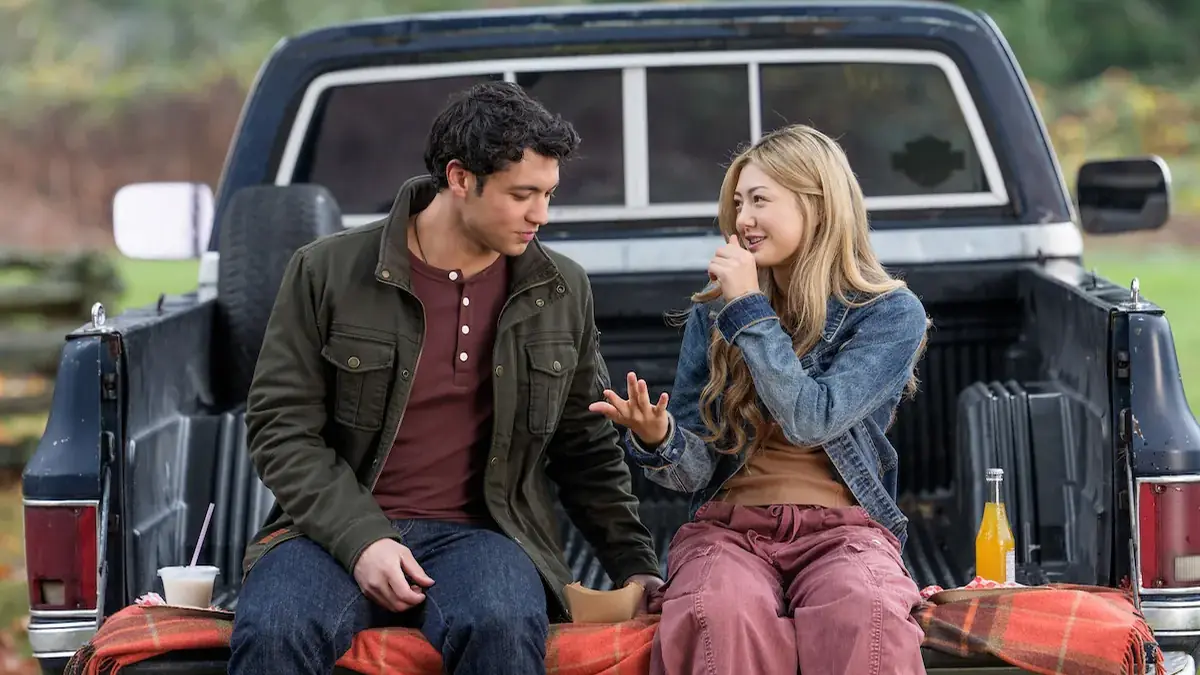 Miku Martineau as Teagan Tao sits with Kyle Clark as Cam Dillinger beside a lake in Crew Girl