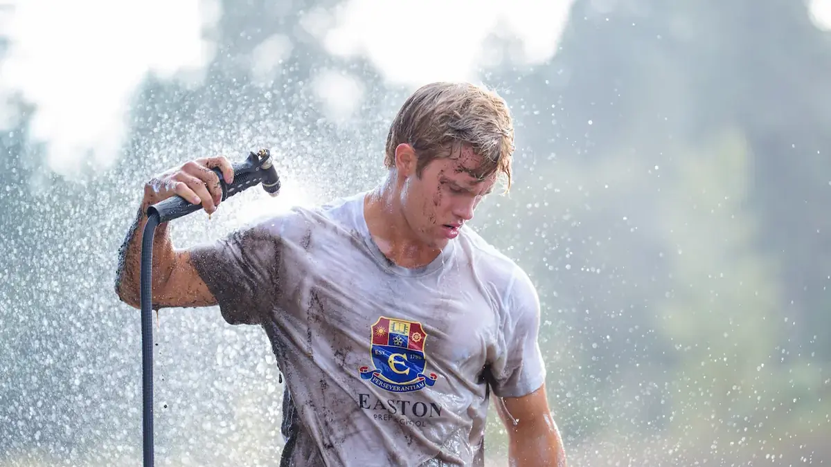 Sam Braun as Josh Regis rinses mud from his Easton Prep rowing shirt in Crew Girl