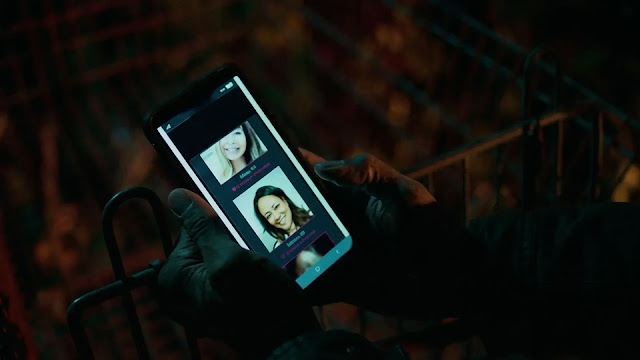A smartphone showing a dating app profile in a dark room