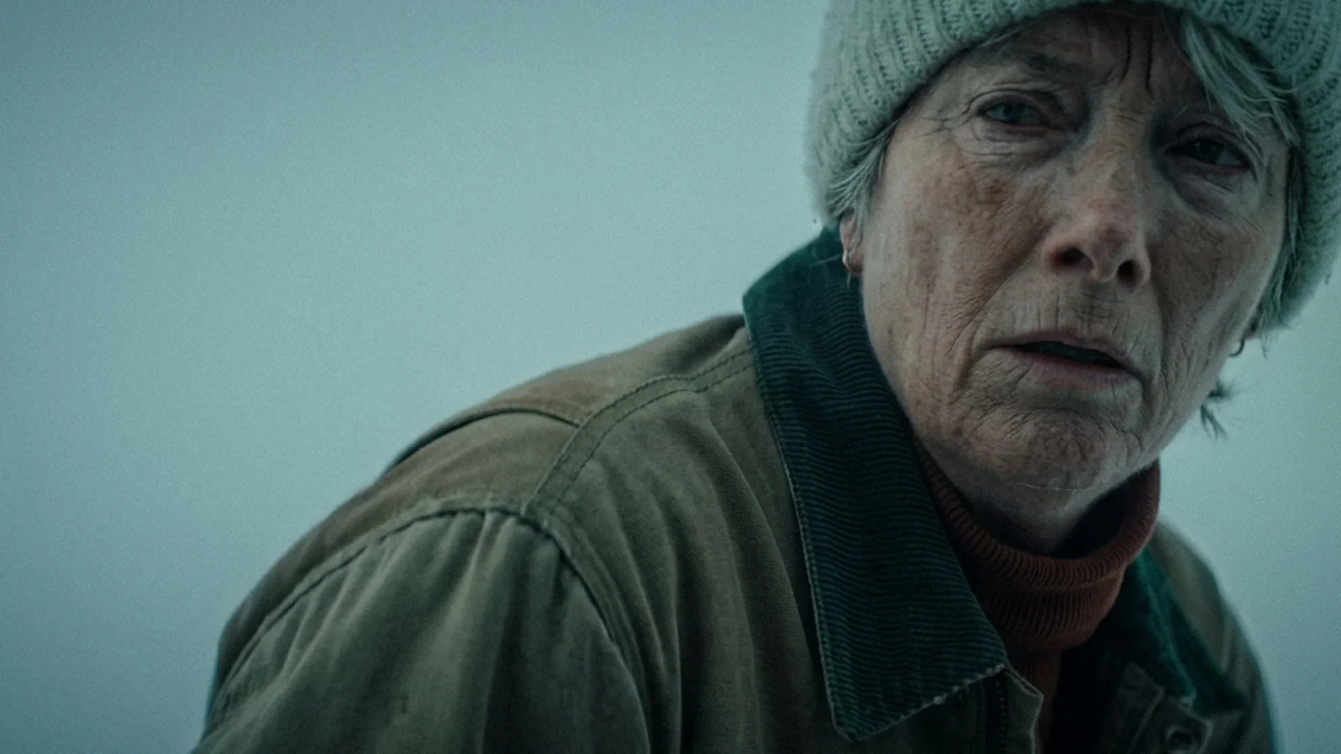 Emma Thompson as Barb, bundled in a knit hat, watches warily in the snow in Dead of Winter