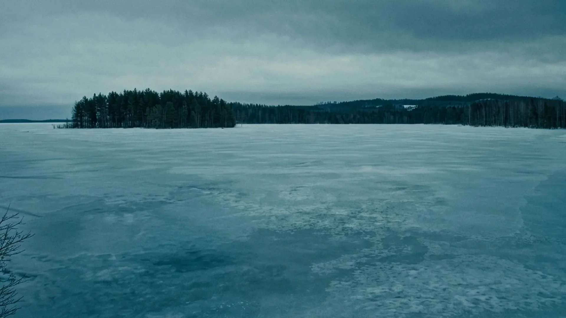 A frozen lake stretches to the treeline under a cold winter sky in Dead of Winter