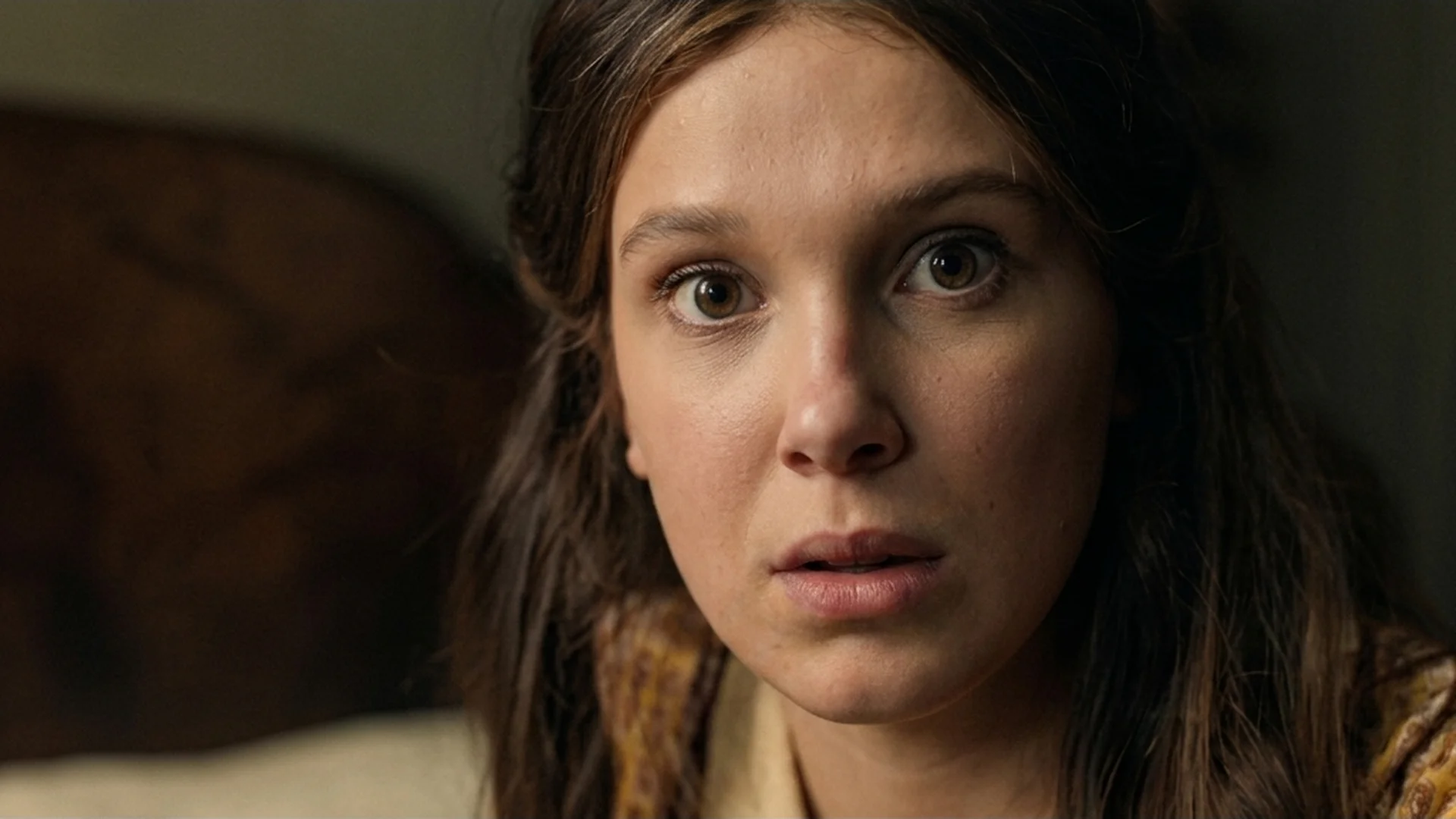 Close-up of Millie Bobby Brown as Enola Holmes meeting the camera with an intense look