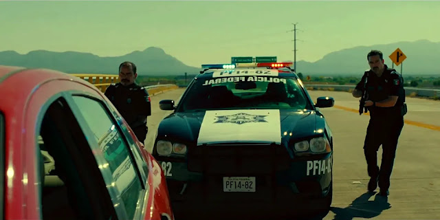 A federal police cruiser stops a red car on an empty desert highway