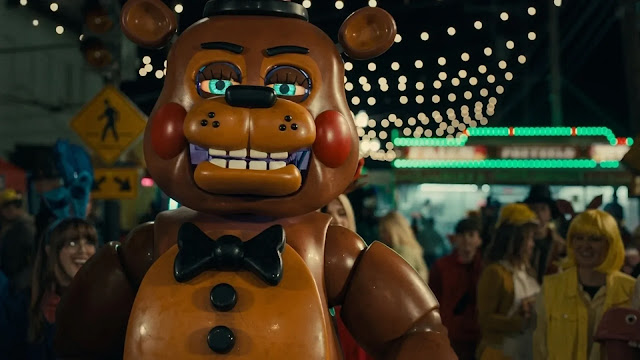 A colorful animatronic Freddy Fazbear stands among a nighttime carnival crowd in the Five Nights at Freddy's 2 trailer