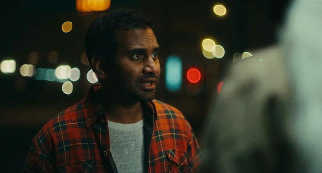 Aziz Ansari as Arj, a weary gig worker, lit by night traffic in Good Fortune