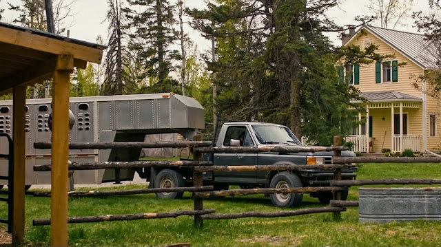 The ranch house, a stock trailer and a pickup truck behind the rail fence in Heartland season 19