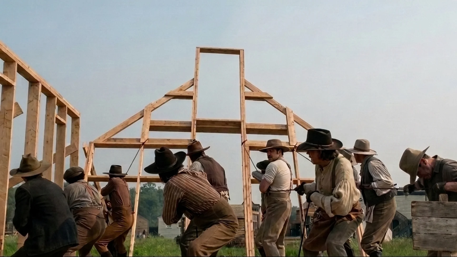 A group of men uses ropes to raise a timber wall frame in Little House on the Prairie.
