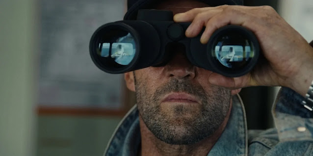 Cole Reed (Jason Statham) watching through binoculars in Mutiny, a vessel reflected in both lenses