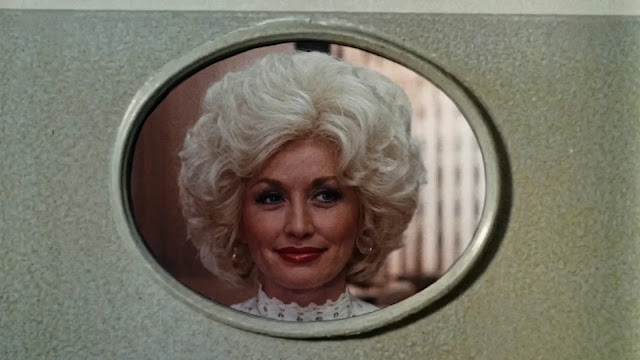 Doralee (Dolly Parton) framed in an oval office window in 9 to 5