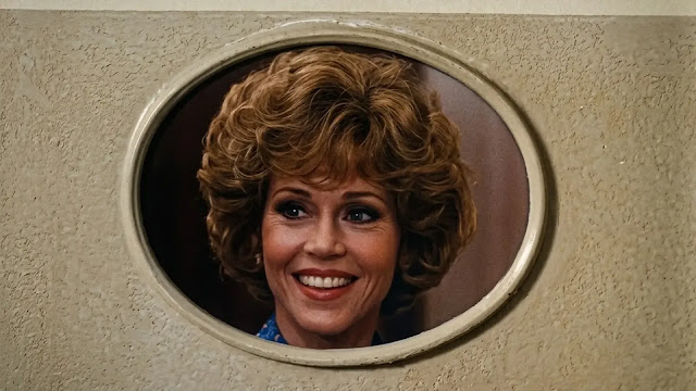 Judy (Jane Fonda) seen through an oval opening in an office partition in 9 to 5