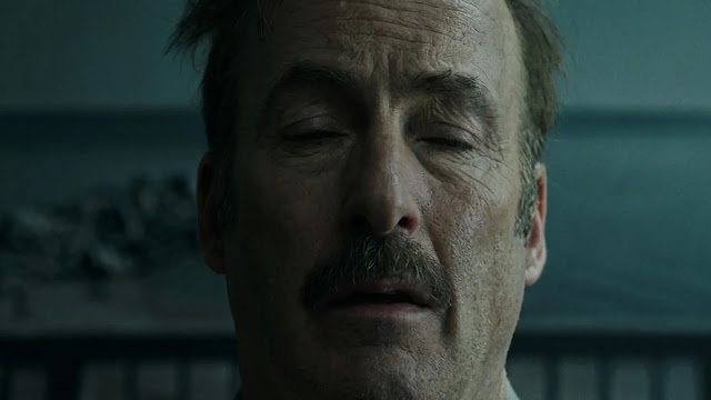 Bob Odenkirk as Sheriff Ulysses in a close-up outdoors by grey water