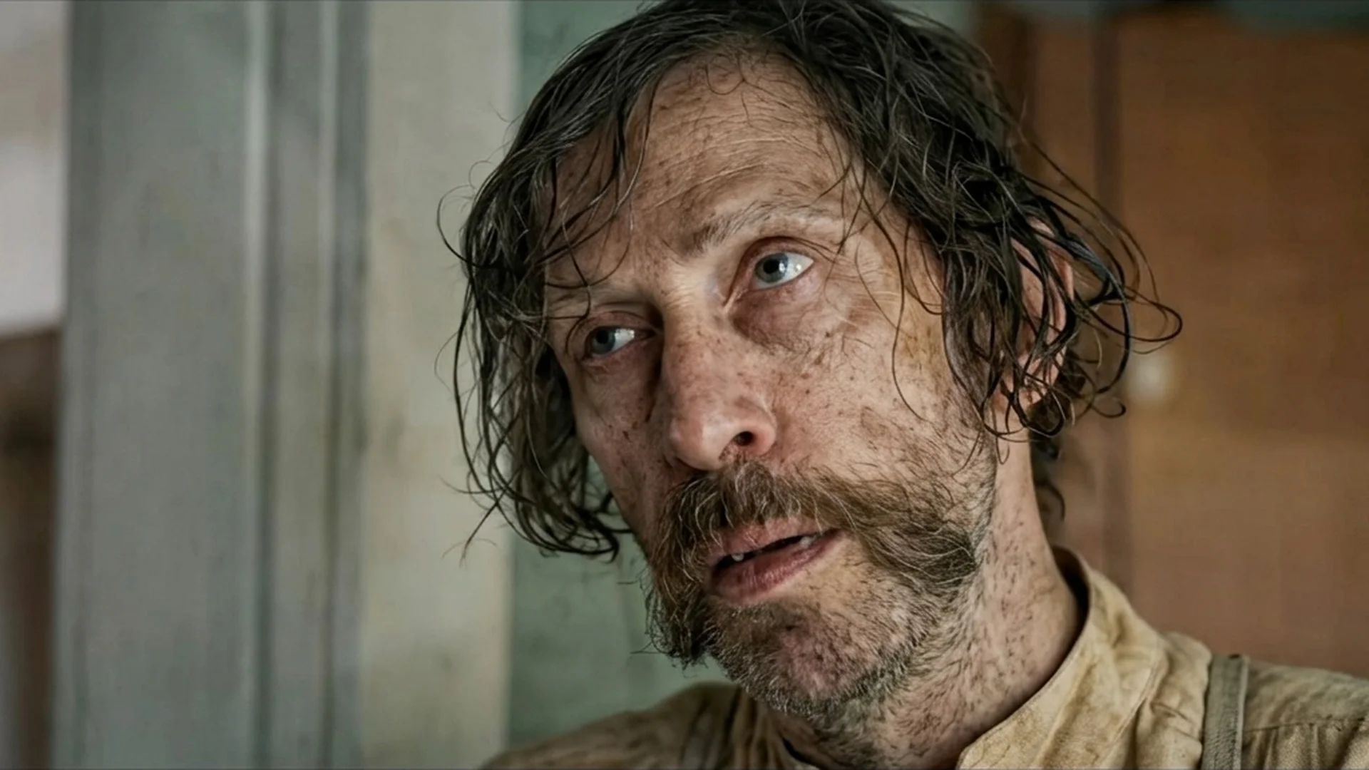 Weathered close-up of Tim Blake Nelson as Henry, hair loose and expression worn, in the Old Henry trailer