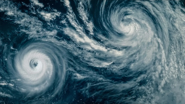 A pair of storm systems swirling over the ocean