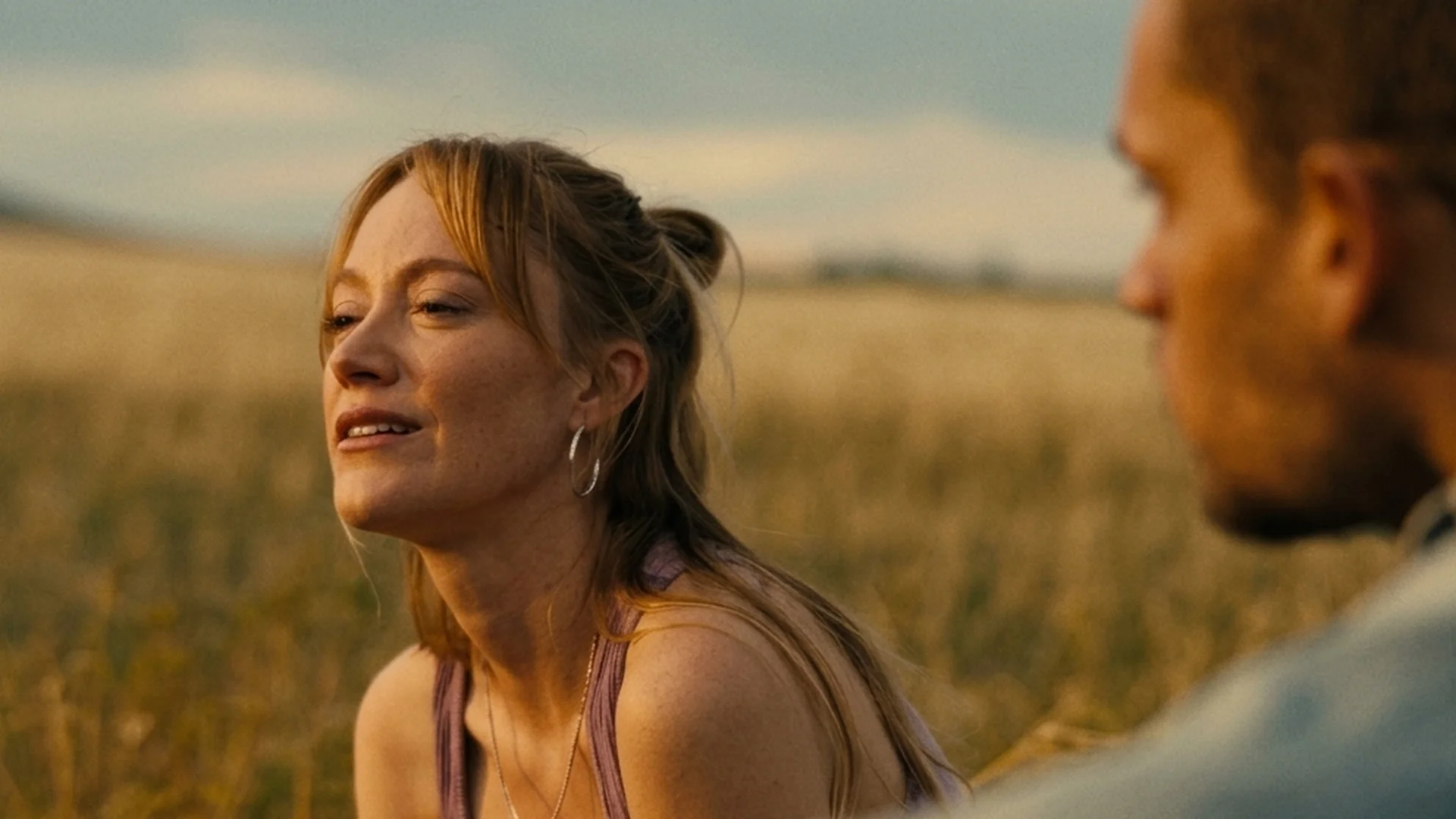 Kenna and Ledger sit face to face in a sunlit golden field in Reminders of Him