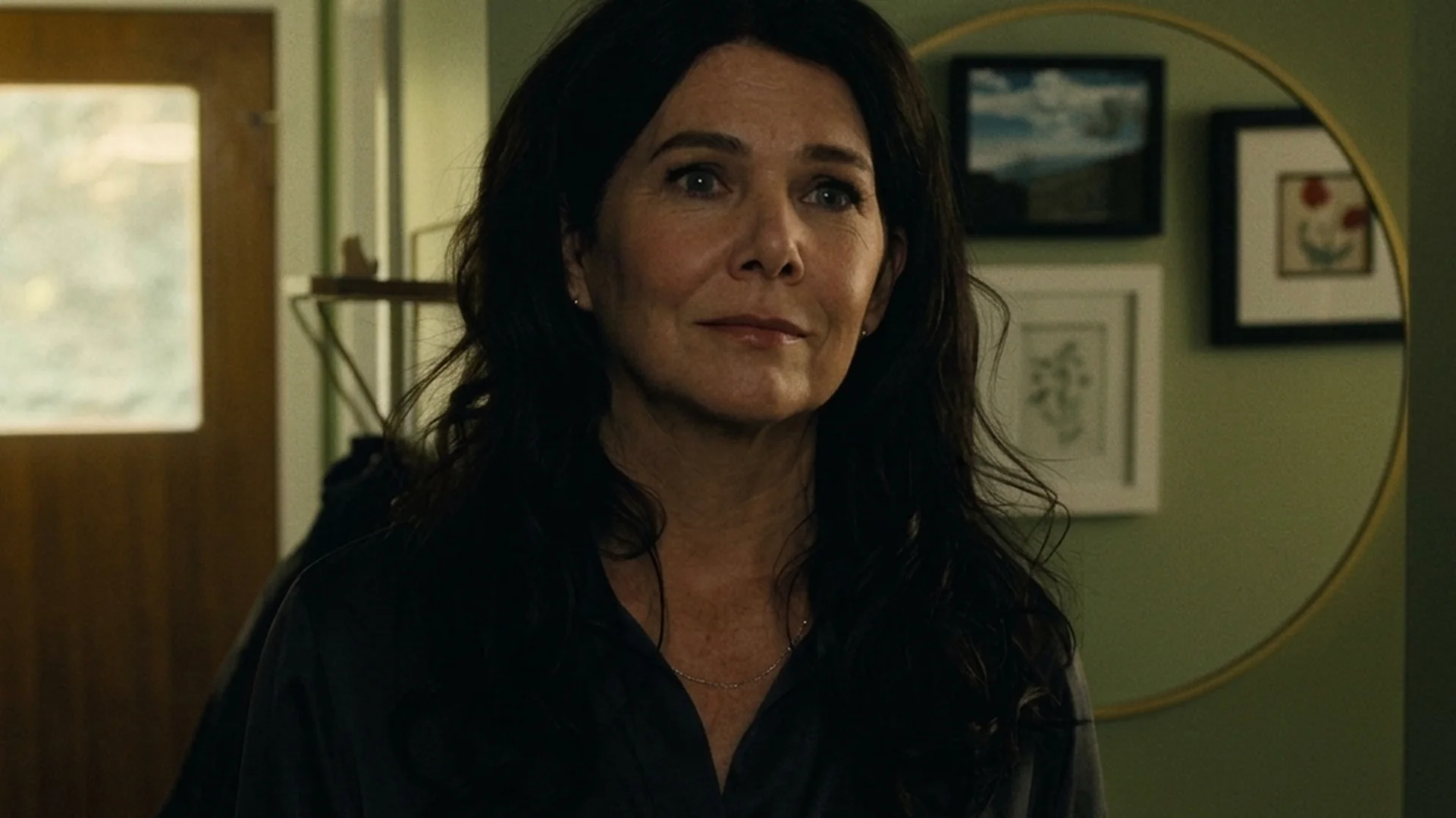 Lauren Graham as Grace stands in a room with a wary, guarded expression in Reminders of Him
