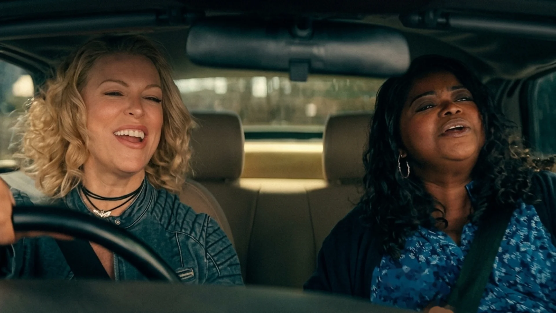 Judith (Hannah Waddingham) drives while Debbie (Octavia Spencer) sings along beside her, both laughing in the car