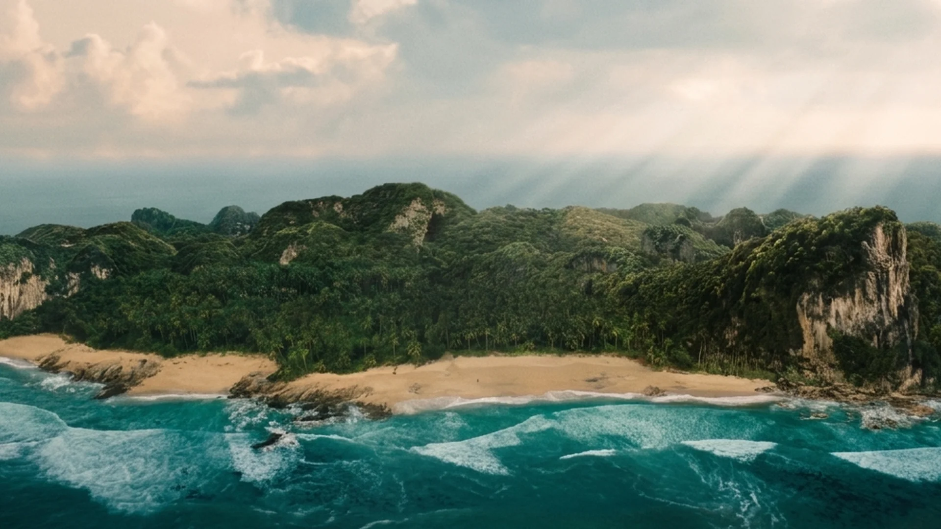 Aerial view of a tropical island with a sandy cove, dense green jungle, limestone cliffs and turquoise surf in Send Help