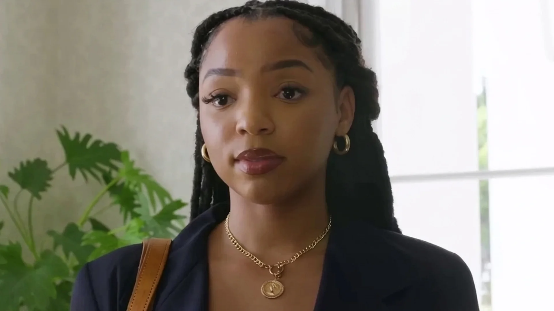 Chloe Bailey as Laila looks warily across a bright mansion room in Strung