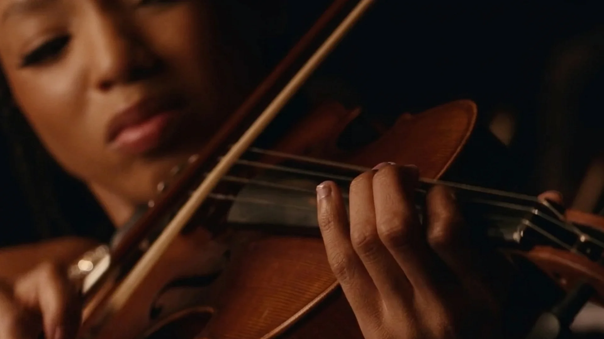 Laila plays the violin with her eyes down in concentration in Strung