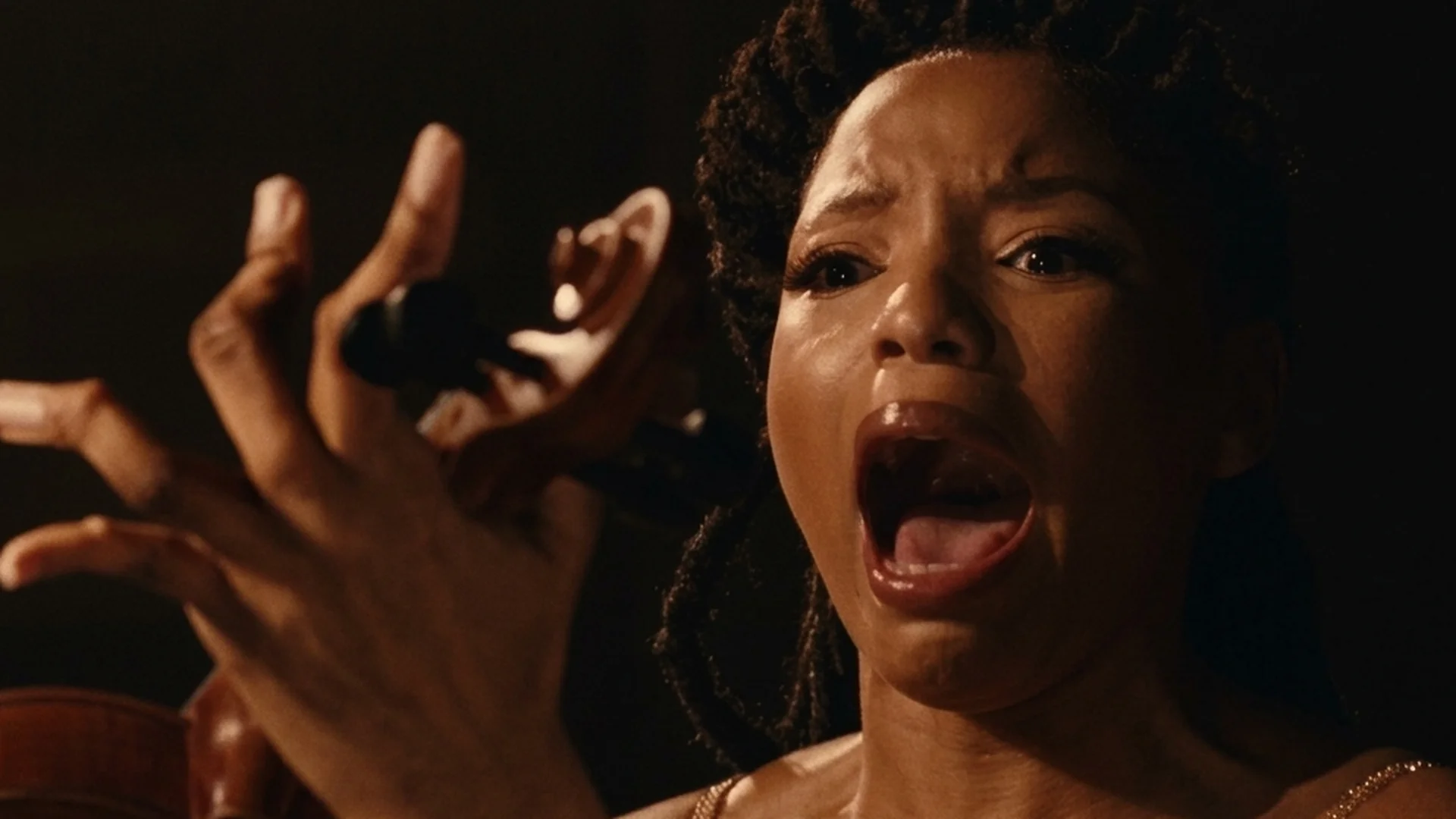 Laila screams with her hand raised in terror in Strung