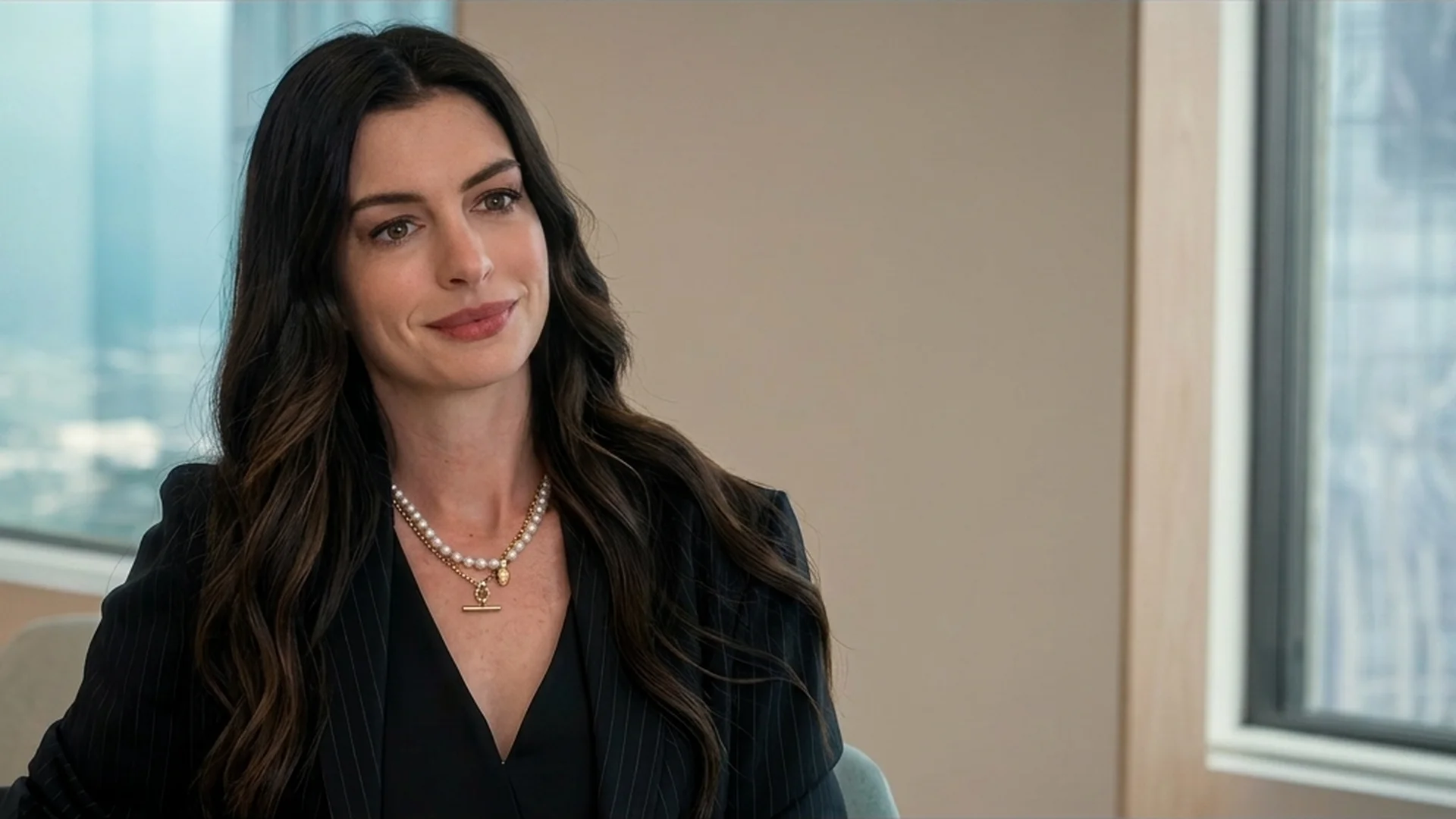 Anne Hathaway as Andy Sachs in a dark suit and pearl necklace in The Devil Wears Prada 2