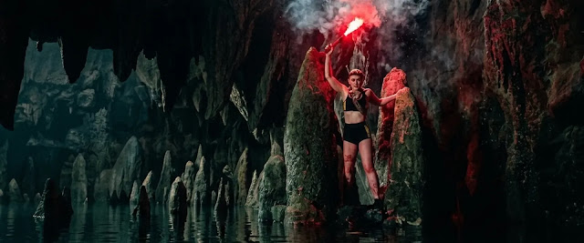 Sara (Kathryn Newton) holds a lit flare in the flooded cave