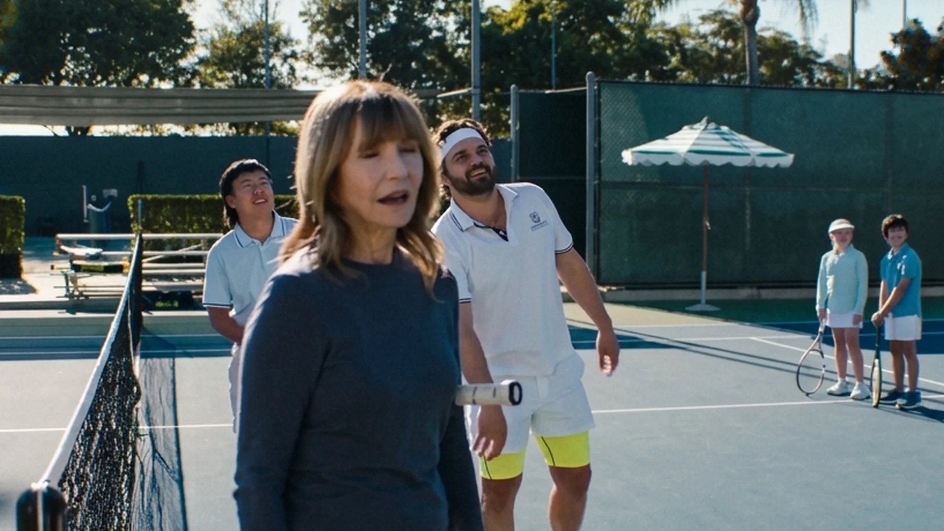 Mary Steenburgen and Jake Johnson stand together by the net on a pickleball court.