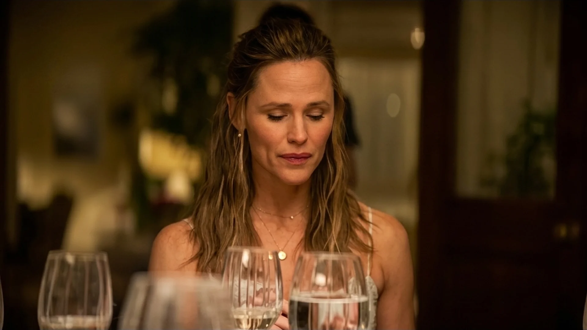 Hollis (Jennifer Garner) at the candlelit dinner table, eyes lowered as she takes in hard news