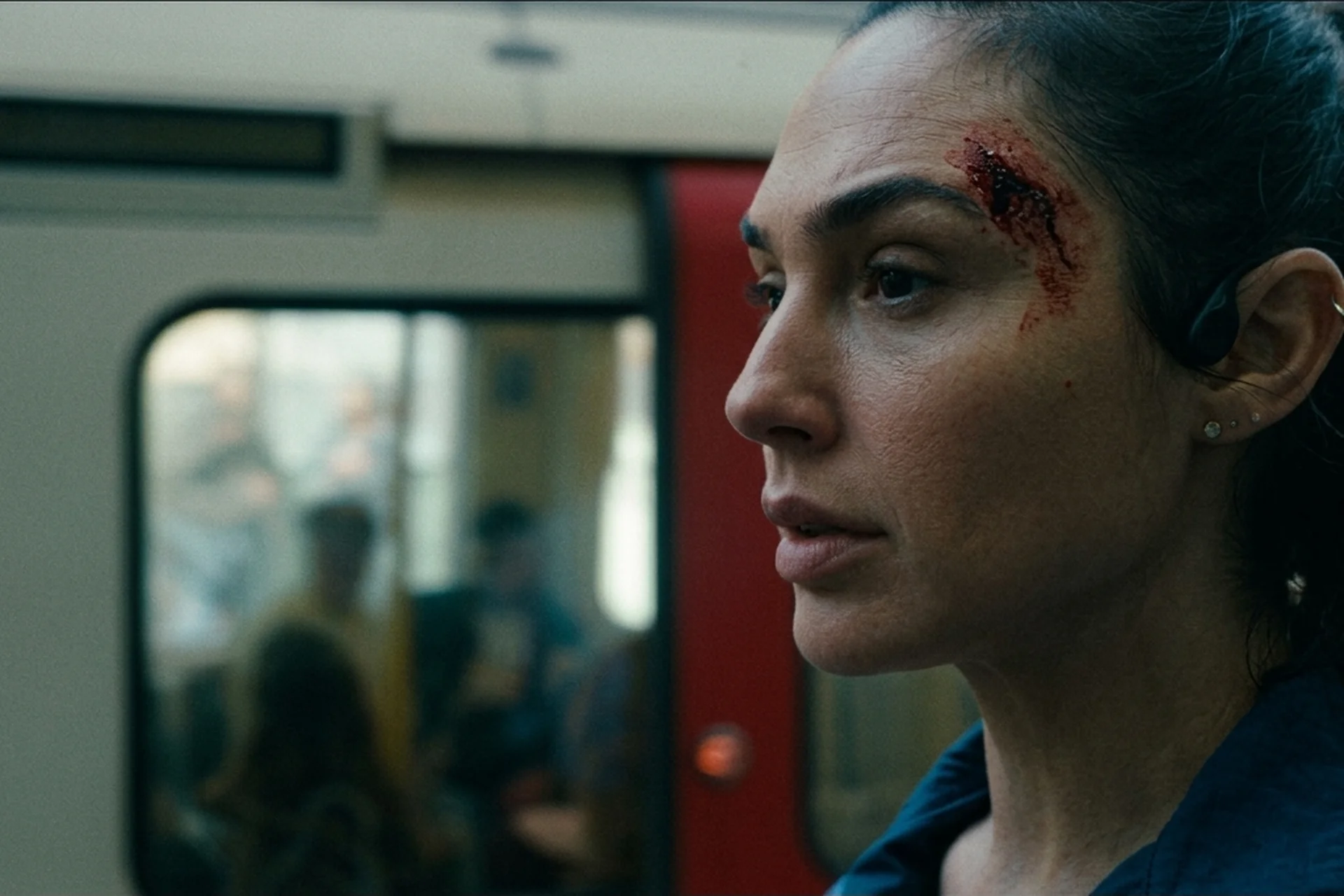 Maia with a cut above her eyebrow after being hit by a car, standing beside a train in The Runner