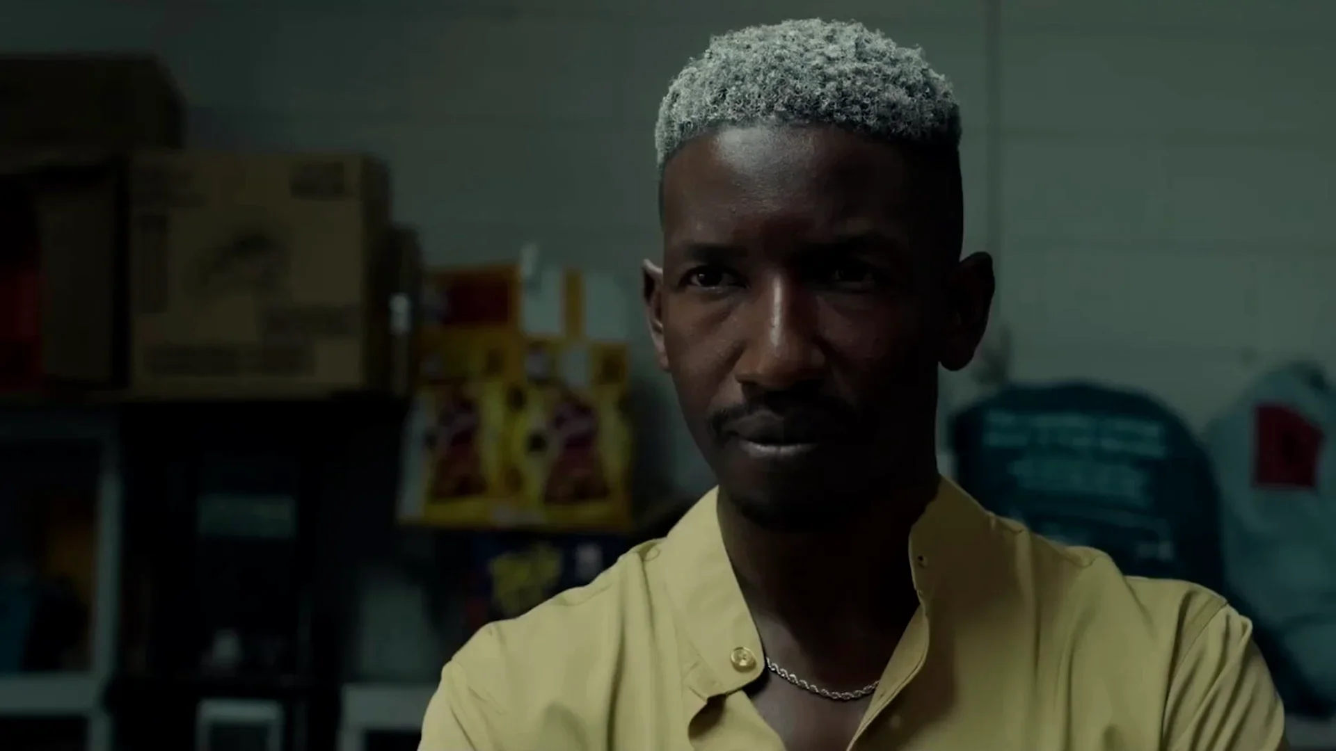 Mamoudou Athie as Oscar stands in a dim convenience-store stockroom in Wardriver