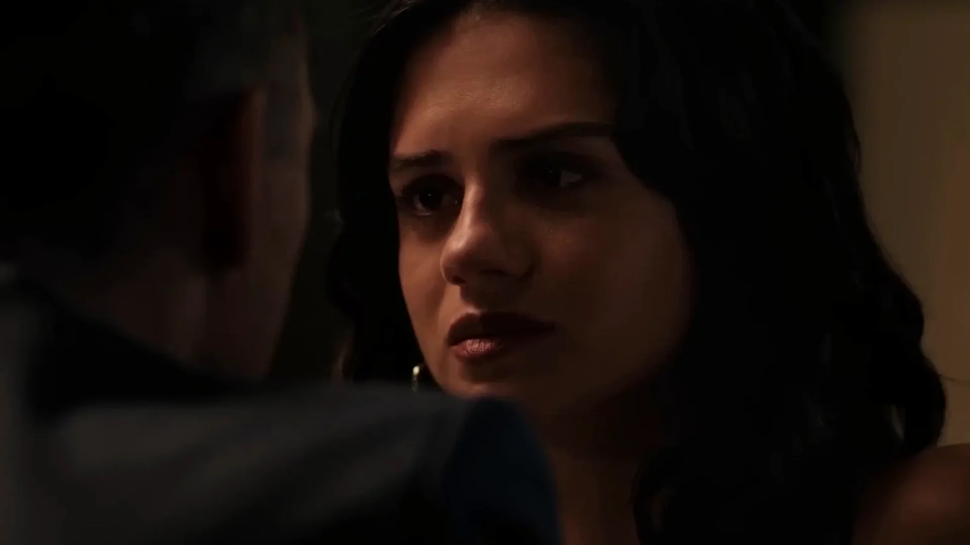 Sasha Calle as Sarah looks at Cole, whose back is to the camera, in a dim room in Wardriver