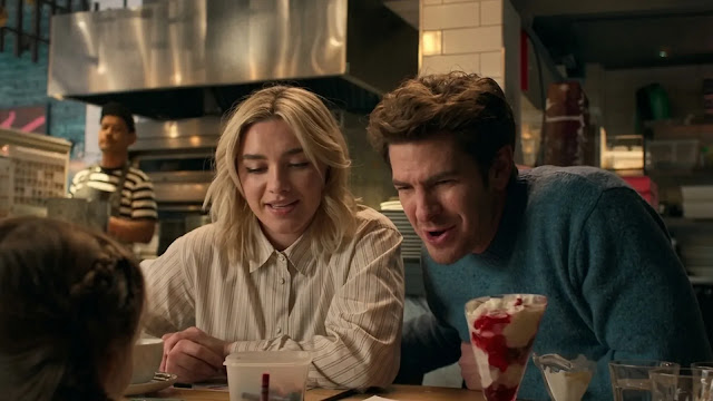 Almut (Florence Pugh) and Tobias (Andrew Garfield) sit close together at a pizzeria counter with a sundae between them, both smiling, in the We Live in Time trailer