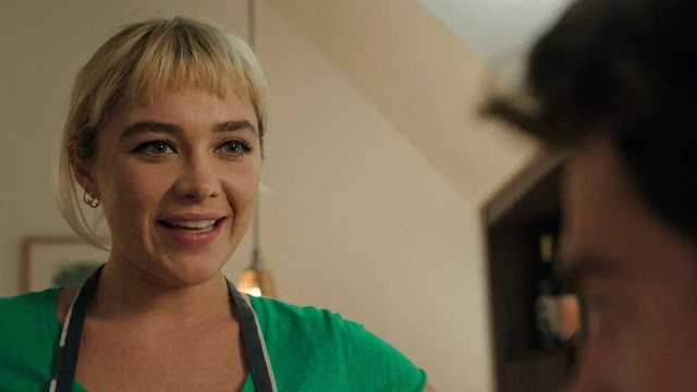 Almut (Florence Pugh) smiles while wearing a green apron in a kitchen in the We Live in Time trailer